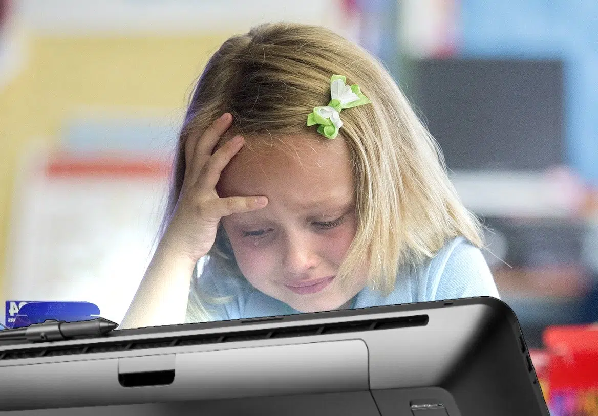 Young girl crying while drawing on a tablet.
